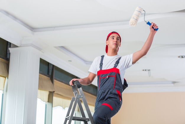 Young painter painting the ceiling in construction concept