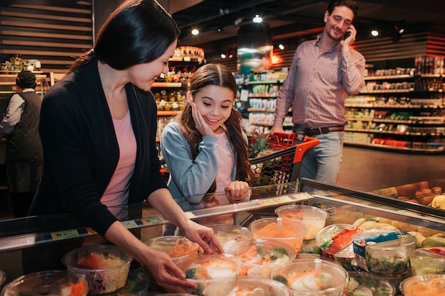 若い親とサラダを選択する食料品店の娘