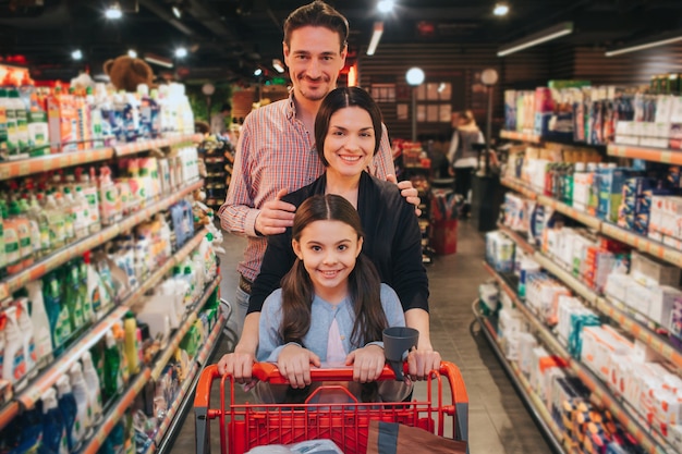 Young parents and daughter in grocery store pushing a chart