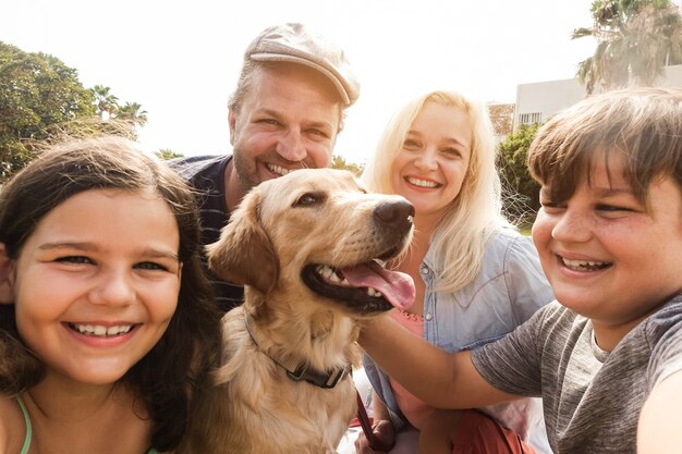 Young parents having fun with children and their pet outdoor at park in summer time 