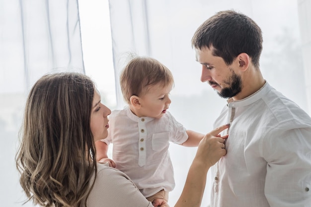 Young parents hold a baby in their arms and stand near the window in their new apartment High quality photo