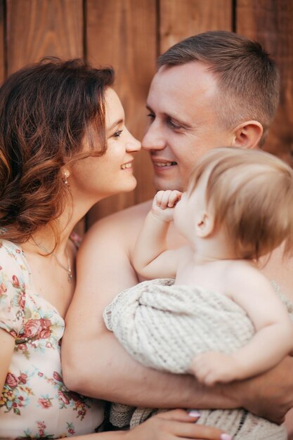 Young parents hold their little son in the summer garden