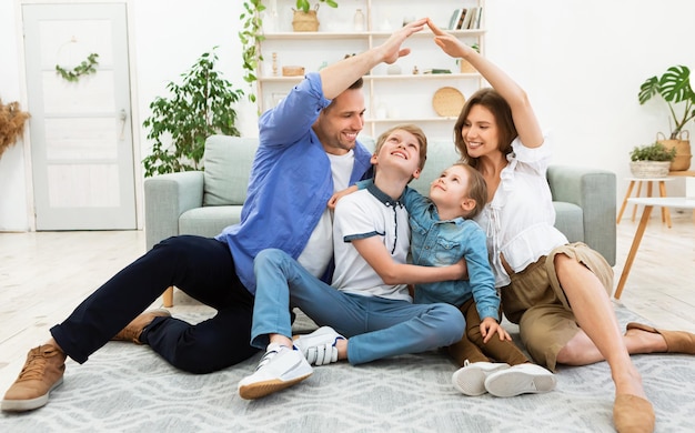 young parents joining hands making roof sitting with children indoor