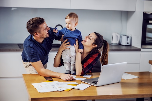 young parents paying bills online for home with some help of their beloved only son. home interior.