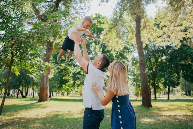 Young parents play in the park with their son