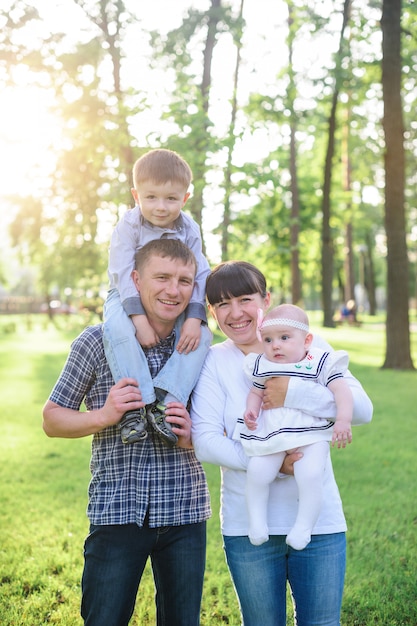 Young parents with children walk in the summer park