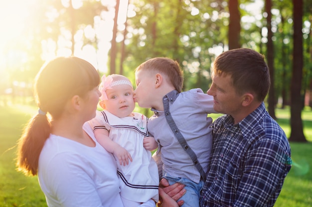 Young parents with children walk in the summer park