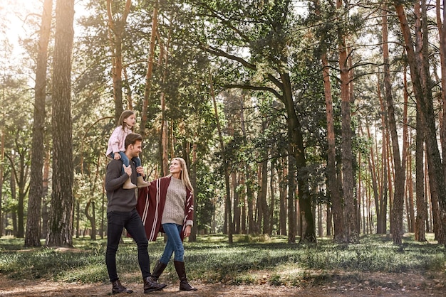 Young parents with little daughter in autumn forest side view