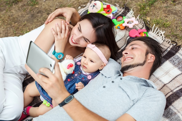 Young parents with a small child have fun and watch a movie on a tablet