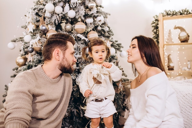 Young parents with a small daughter near the Christmas tree