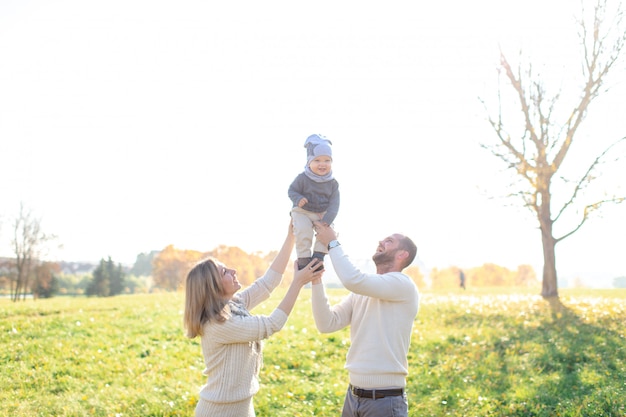 Giovani genitori con il loro bambino che trascorrono del tempo in autunno parco.