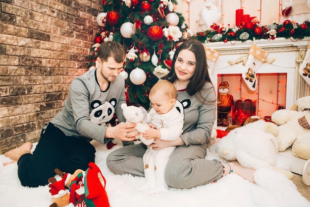 Giovani genitori con il giovane figlio vicino all'albero di natale