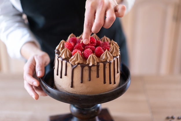 부엌에서 과일과 함께 맛있는 수제 초콜릿 케이크를 요리하는 젊은 생과자 요리사