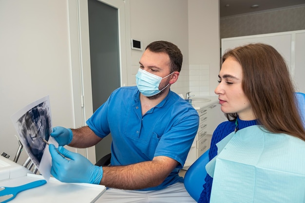 Photo a young patient in dentistry looks at a freshly taken picture of his teeth for further treatment dental treatment concept