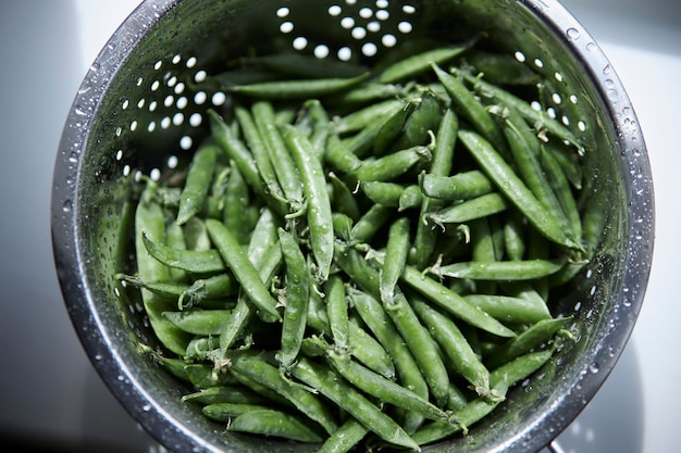 Young peas in pods in an iron colander Diet healthy eating