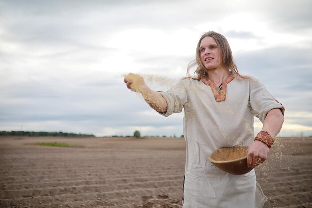 A young peasant of the Scandinavian appearance sows the field with grainxA