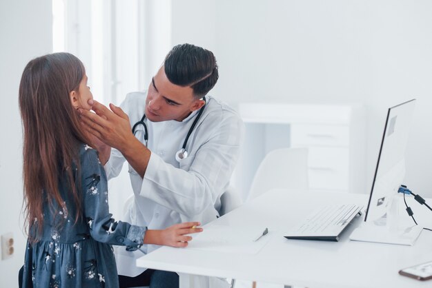 Young pediatrician works with little female visitor in the clinic.