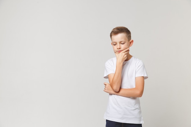 Young pensive boy holding his chin on white background