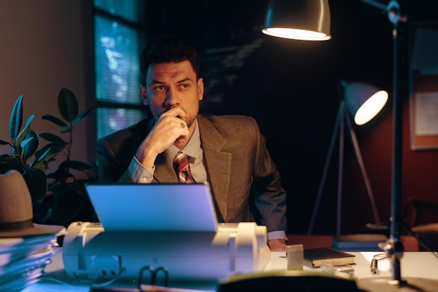 Young pensive businessman in elegant suit keeping hand by his face