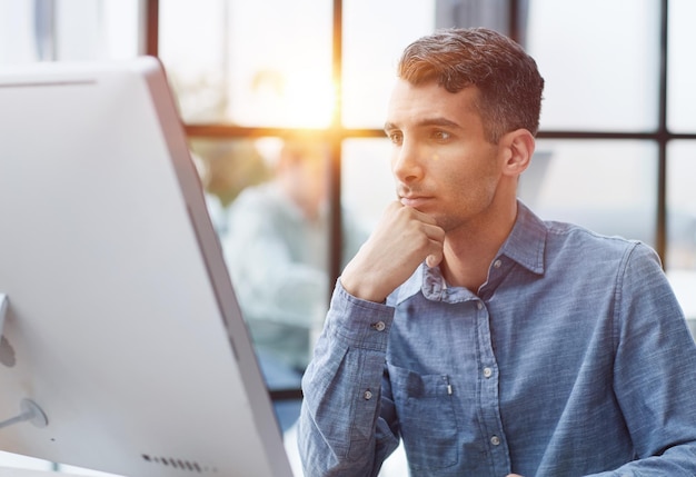 a young pensive man works in the office and thinks about something