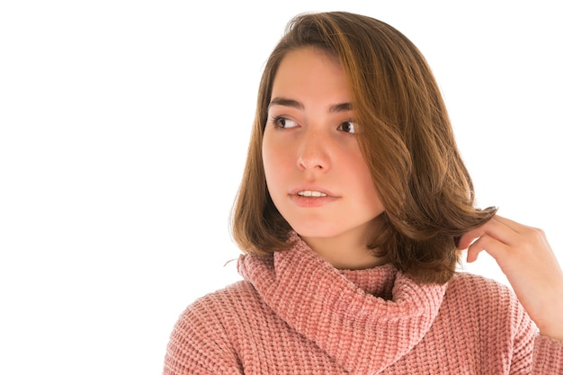 Giovane donna pensierosa in maglione rosa isolato su bianco