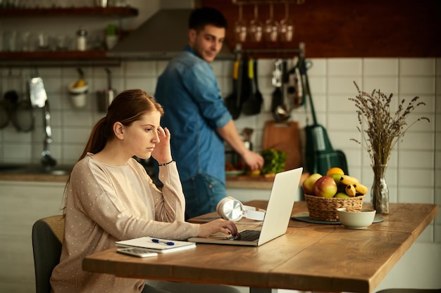 Young pensive woman reading an email on laptop at home