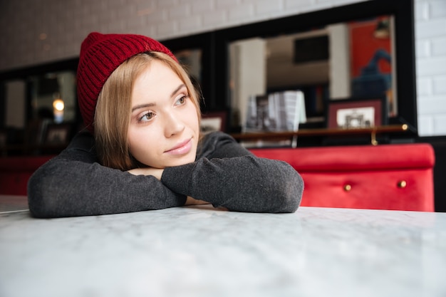 Young pensive woman in red hat lying on the table