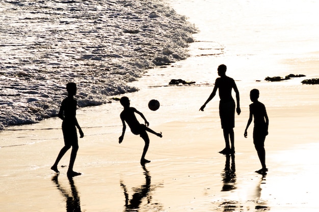 Young people are seen in silhouette playing beach soccer in the city of Salvador Bahia