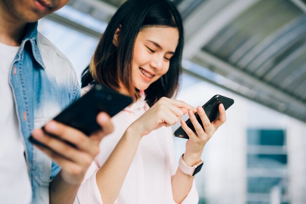 Young people are using smartphone and smiling while sitting on free time. technology concept