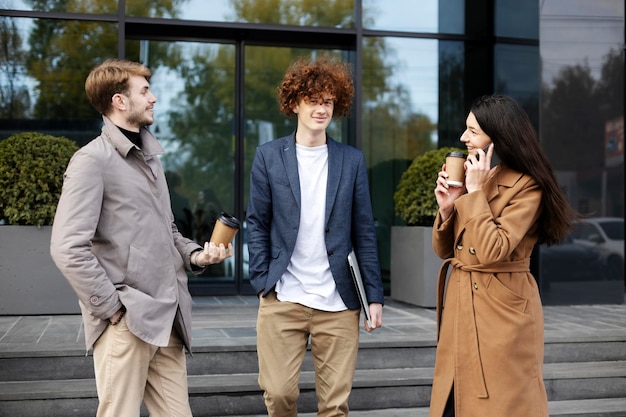 Young people communicate on street near modern glass building Girl talking on mobile phone