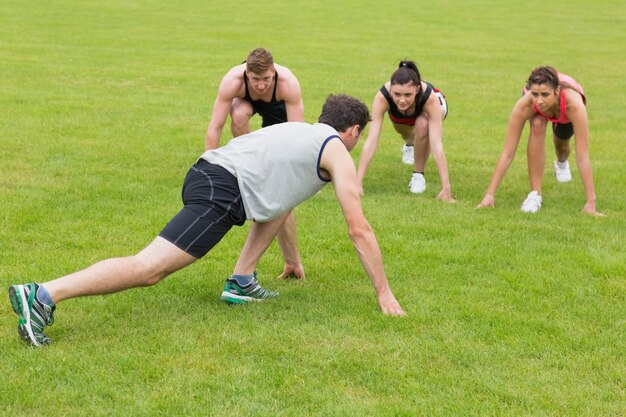 Photo young people doing stretching exercise at the park