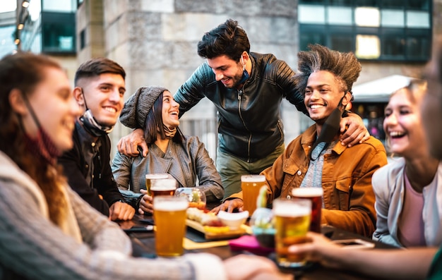 Giovani che bevono birra con la mascherina aperta