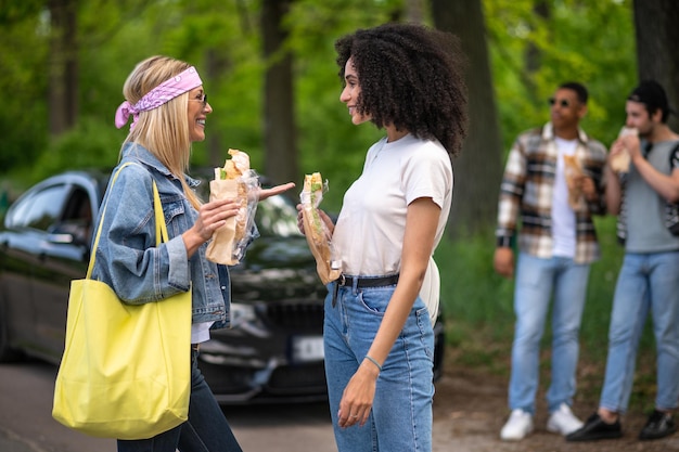 Young people eating sandwiches and looking joyful