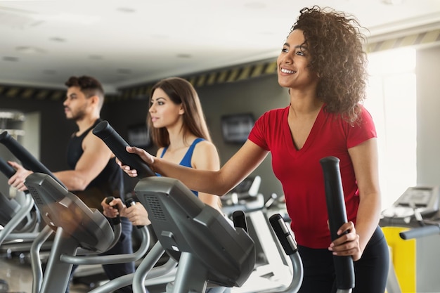 Young people exercising on cardio stepper in gym