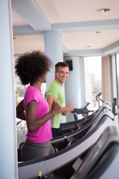 Photo young people exercisinng a cardio on treadmill running chine in modern gym