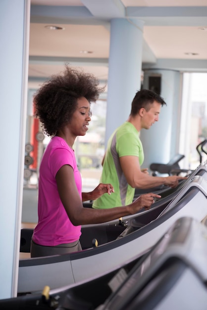 young people exercisinng a cardio on treadmill running chine in modern gym