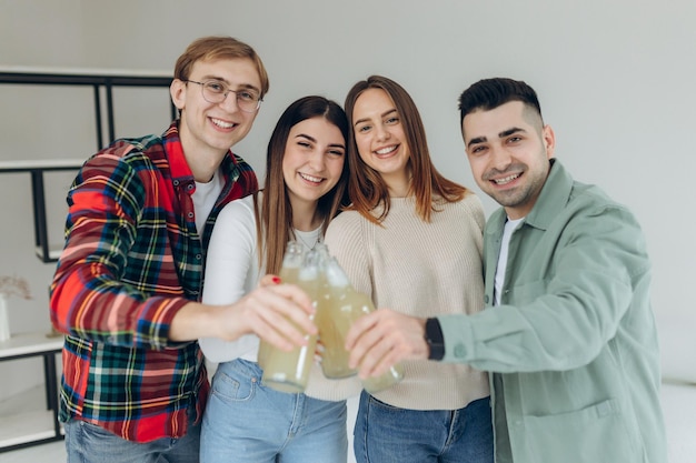 Young people having fun on the weekend group of friends
enjoying drinks and good time together happy girls and boys laugh
and splash bottles of beer after a funny toast