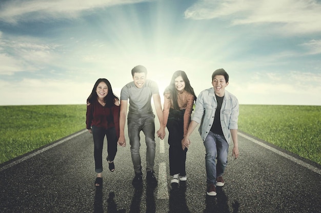 Young people hold hands and walk on the road