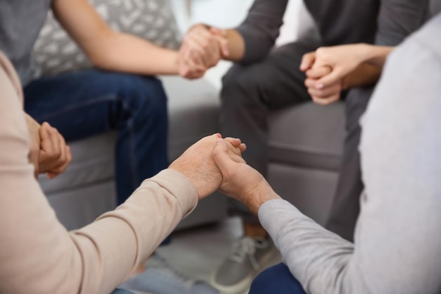 Young people holding hands during group therapy closeup