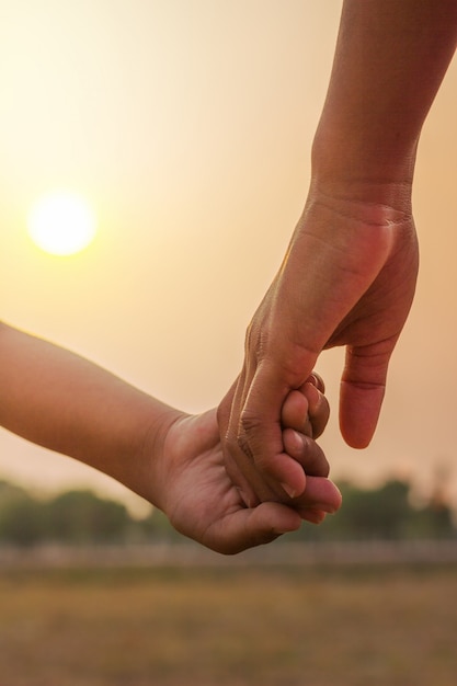 Foto giovani che si tengono per mano sul tramonto.