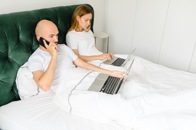 Young people at home or millennial beautiful couple in the hotel using internet connection and technology devices like computer laptop.