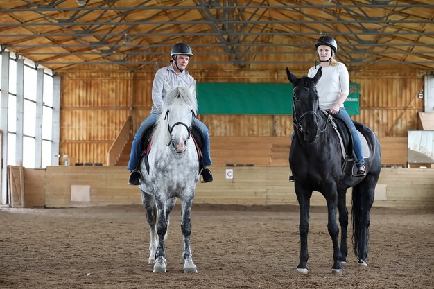 Young people on a horse training in a wooden arena