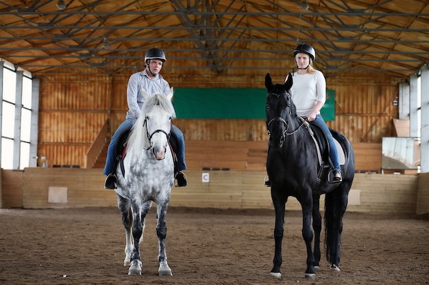 Young people on a horse training in a wooden arena