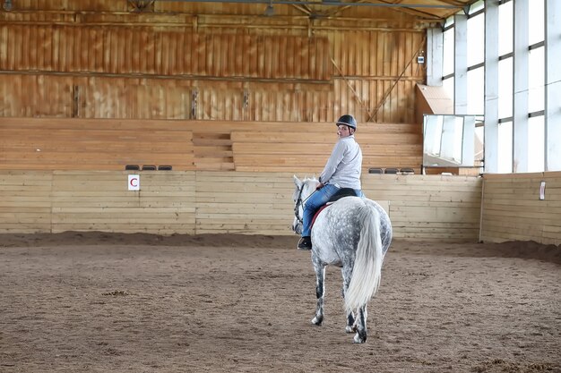 Young people on a horse training in a wooden arena