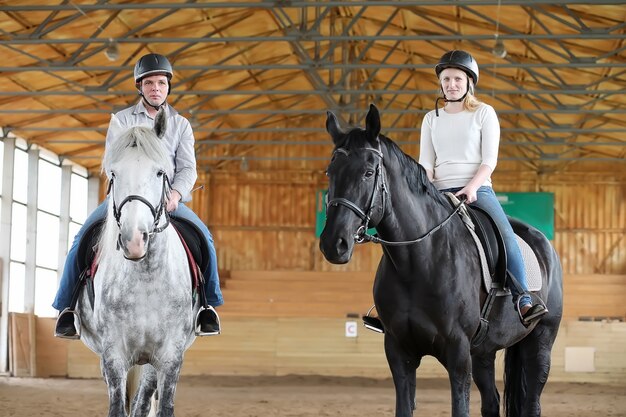 Young people on a horse training in a wooden arena