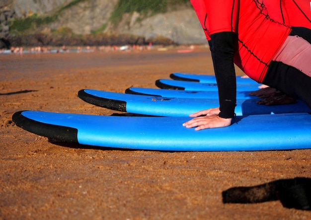 Young people learning to surf on blue surfboards at the seaside