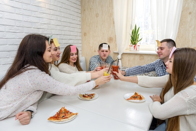 Молодые люди играют в угадайку, пока едят пиццу в кафе