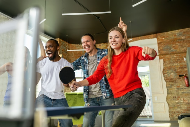 Young people playing table tennis in workplace, having fun