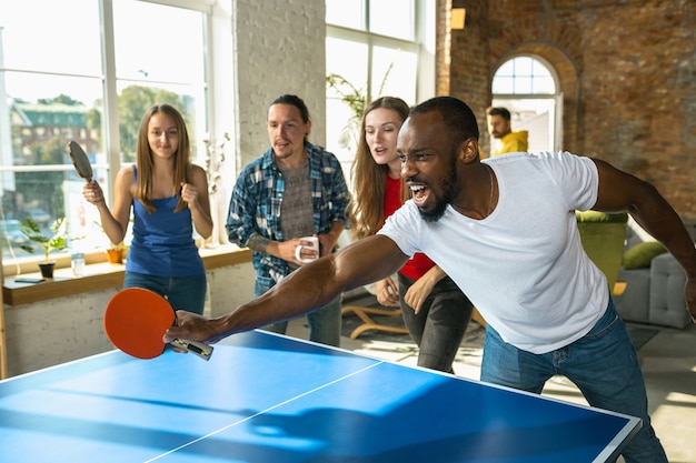 Giovani che giocano a ping pong sul posto di lavoro, divertendosi