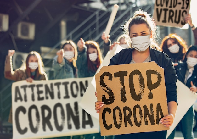 Young people protesting of stop coronavirus pandemic on the street. Caucasian women have meeting about problem in medicine, healthcare system, danger epidemic. Copyspace. Stop coronavirus, COVID-19.